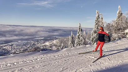 Langläuferin im roten Outfit auf verschneiter Loipe mit Bergblick