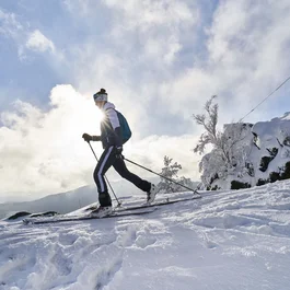 Skifahrer auf verschneitem Berg mit Kreuz bei klarem Himmel