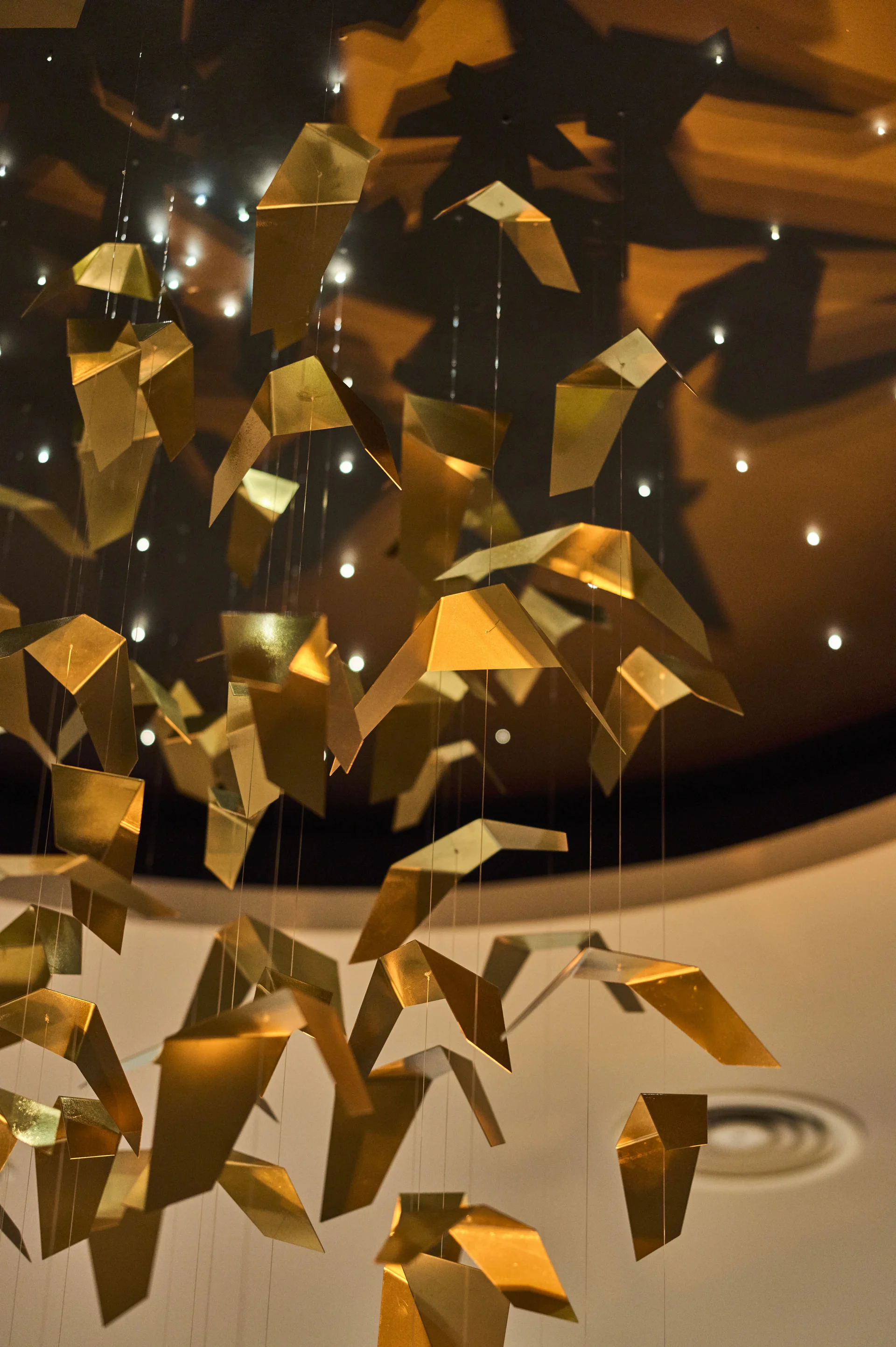 Goldene Origami-Figuren hängen als mobile dekorative Installation an Drähten