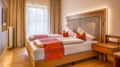 Gemütliches Hotelzimmer mit Doppelbett und orangefarbenen Akzenten