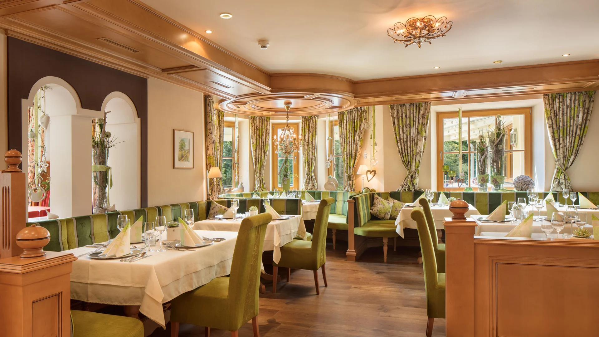Gemütlicher Restaurantbereich mit grünen Stühlen und dekorierten Tischen